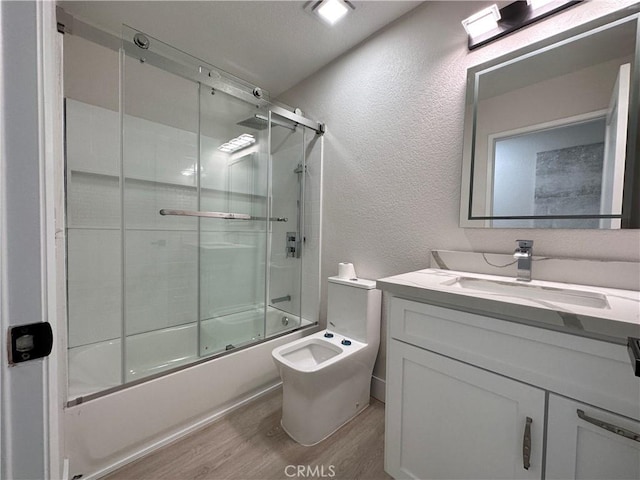 full bathroom with hardwood / wood-style floors, vanity, bath / shower combo with glass door, and toilet