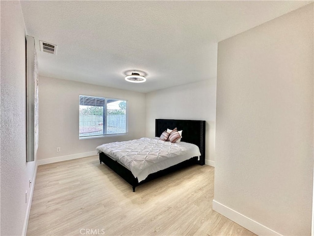 bedroom featuring a textured ceiling and light hardwood / wood-style floors