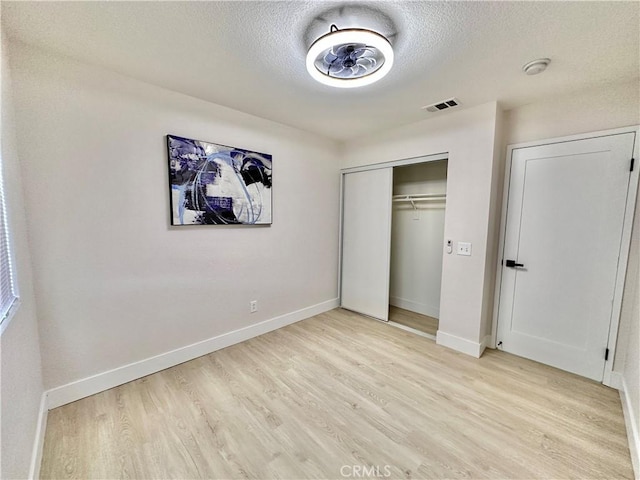 unfurnished bedroom featuring a closet, light hardwood / wood-style floors, and a textured ceiling