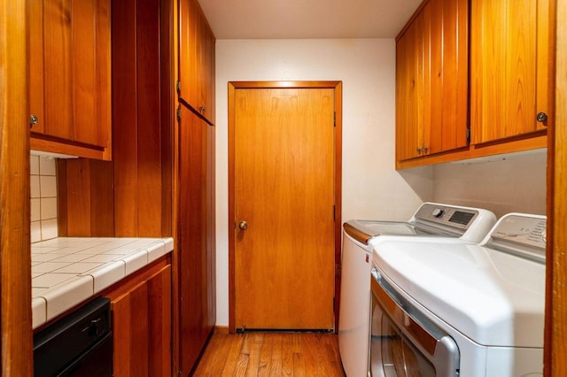 laundry area featuring cabinets, separate washer and dryer, and light hardwood / wood-style flooring