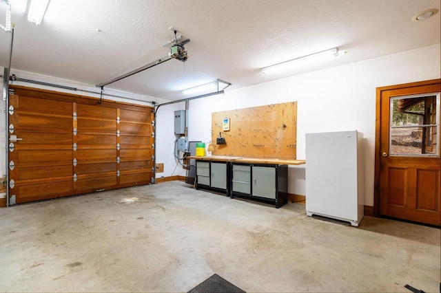 garage with a workshop area, white refrigerator, a garage door opener, and electric panel