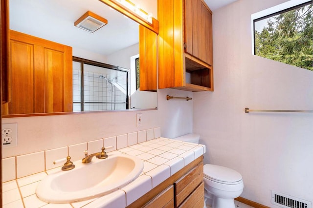 bathroom with a shower with door, vanity, and toilet