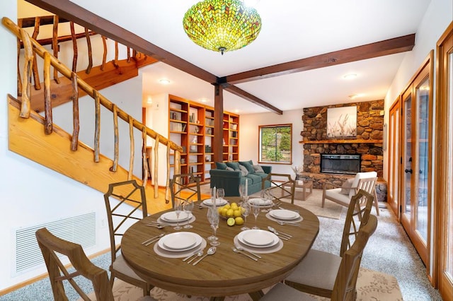 dining space featuring a fireplace, french doors, and beamed ceiling