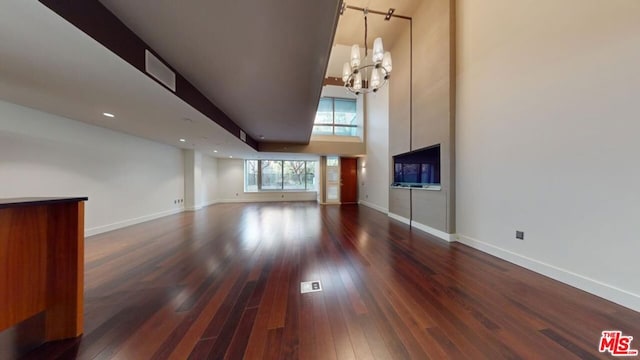 unfurnished living room with dark wood-type flooring and an inviting chandelier