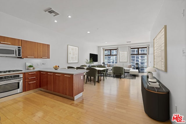 kitchen with kitchen peninsula, light wood-type flooring, and stainless steel appliances