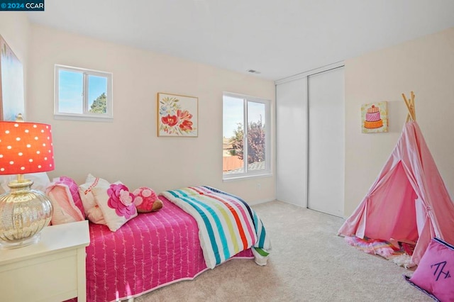 bedroom with a closet, light colored carpet, and multiple windows