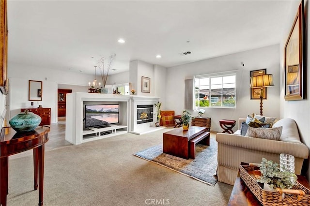 living area featuring carpet, visible vents, recessed lighting, a glass covered fireplace, and a chandelier