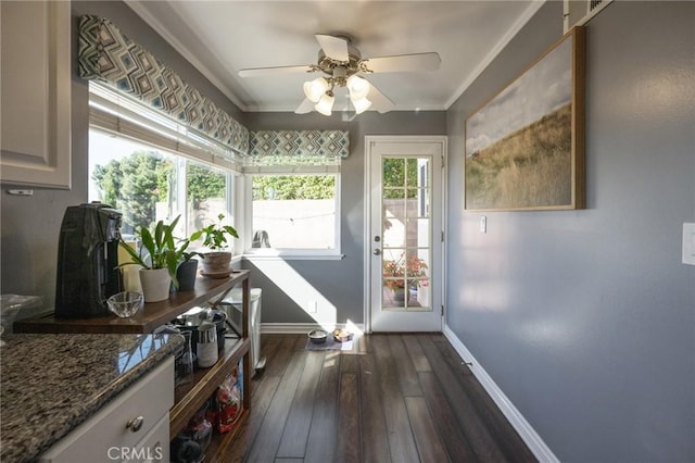 doorway with ornamental molding, ceiling fan, and dark wood-type flooring