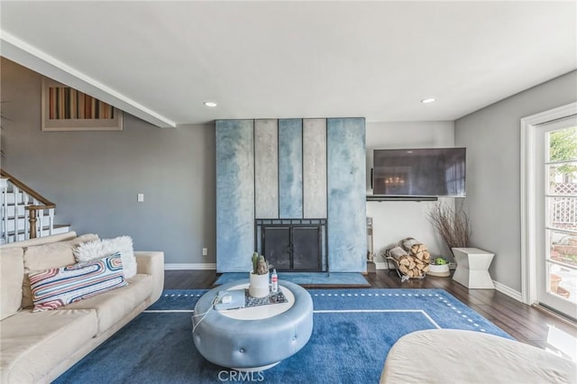 living room with a large fireplace and dark wood-type flooring