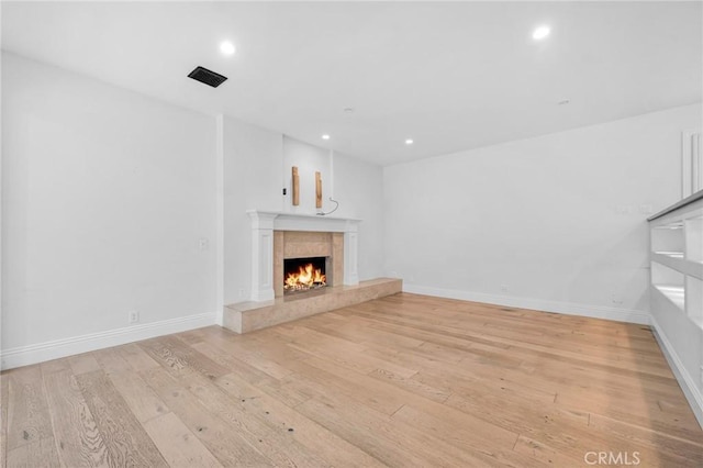 unfurnished living room with light wood-type flooring and a premium fireplace