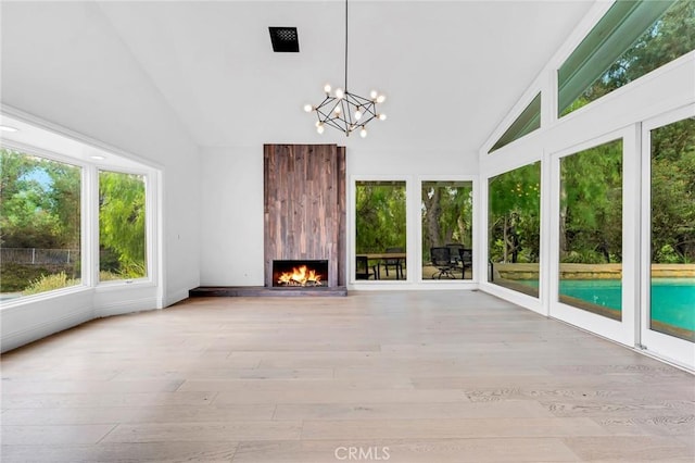 unfurnished sunroom with a large fireplace, a chandelier, and vaulted ceiling