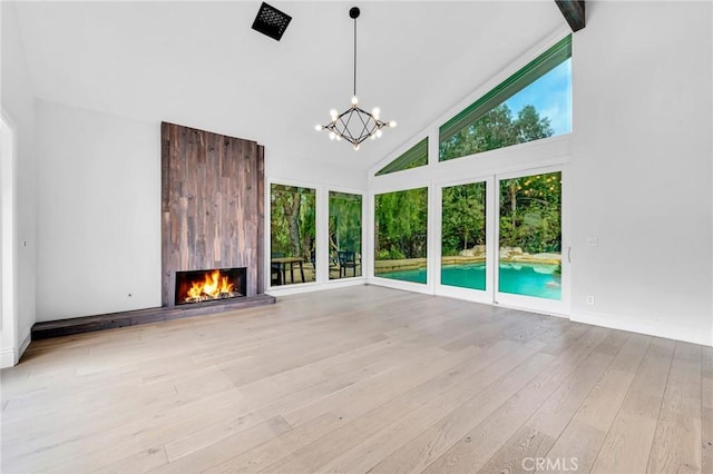 unfurnished living room with a notable chandelier, a large fireplace, high vaulted ceiling, and light hardwood / wood-style flooring