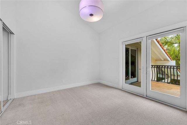 spare room featuring light carpet and lofted ceiling