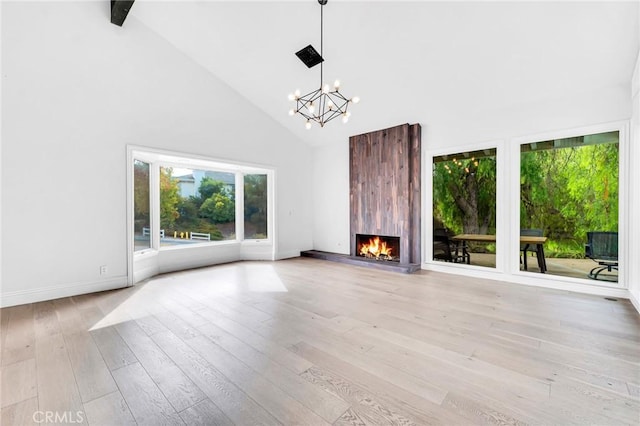 unfurnished living room featuring a large fireplace, light hardwood / wood-style flooring, high vaulted ceiling, and a chandelier