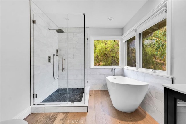 bathroom featuring independent shower and bath, vanity, a healthy amount of sunlight, and hardwood / wood-style flooring