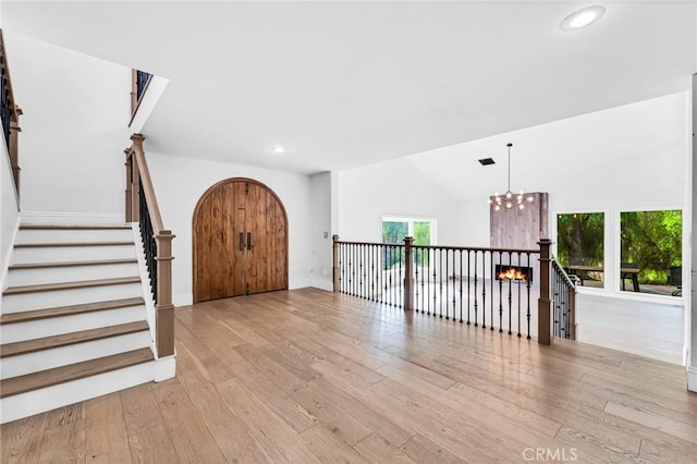 foyer with a chandelier, light hardwood / wood-style floors, and lofted ceiling