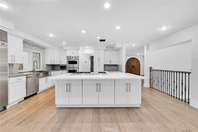 kitchen featuring white cabinets, appliances with stainless steel finishes, light hardwood / wood-style flooring, and a large island