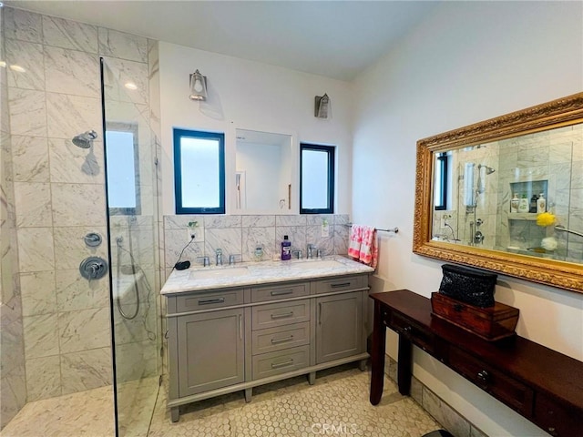 bathroom with tile patterned floors, decorative backsplash, a tile shower, and vanity