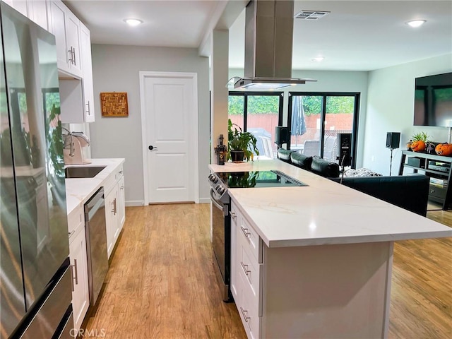 kitchen featuring white cabinets, island exhaust hood, appliances with stainless steel finishes, and light hardwood / wood-style flooring