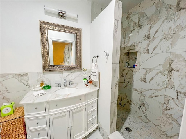 bathroom with vanity, tiled shower, and tile walls