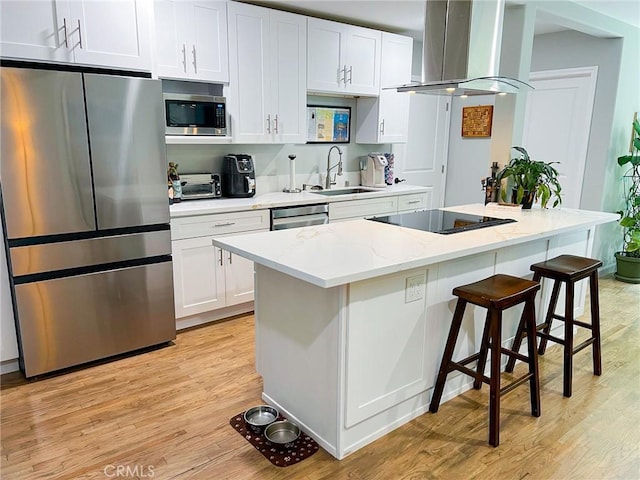 kitchen with appliances with stainless steel finishes, light wood-type flooring, ventilation hood, white cabinets, and a center island