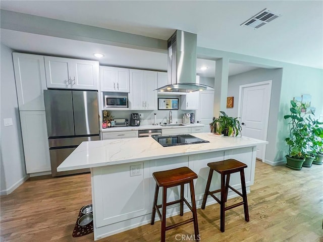 kitchen with sink, a breakfast bar area, white cabinetry, stainless steel appliances, and extractor fan