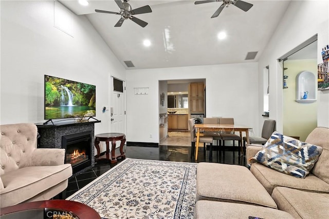 tiled living room featuring ceiling fan, a tile fireplace, and vaulted ceiling