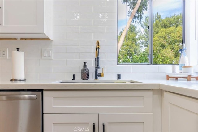 kitchen with white cabinets, tasteful backsplash, stainless steel dishwasher, and sink