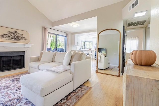 living room with sink, high vaulted ceiling, and light wood-type flooring