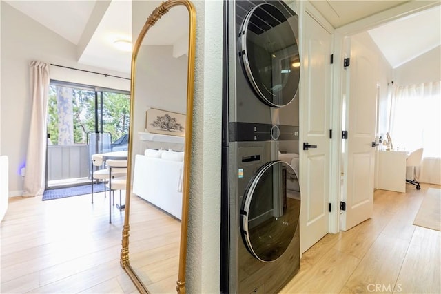 laundry area featuring stacked washer and clothes dryer and light wood-type flooring