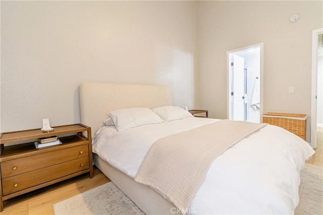 bedroom with connected bathroom and light hardwood / wood-style floors