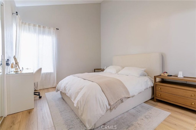 bedroom featuring lofted ceiling and light hardwood / wood-style flooring