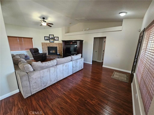 living area featuring lofted ceiling, a tiled fireplace, wood finished floors, and a ceiling fan