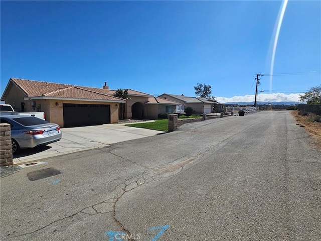 view of front of property featuring an attached garage, a tile roof, driveway, stucco siding, and a chimney