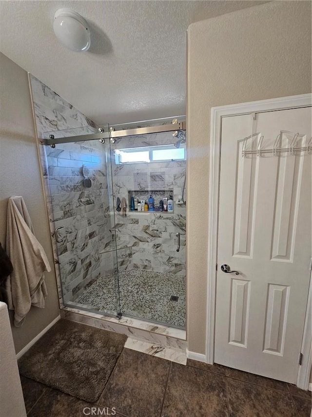 full bath with baseboards, a textured ceiling, and a marble finish shower