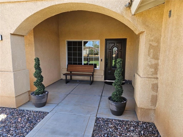 view of exterior entry with a patio area and stucco siding