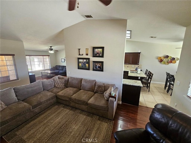 living room with light wood-style floors, lofted ceiling, visible vents, and ceiling fan