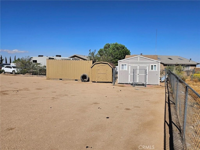 view of yard with an outdoor structure, fence, and a storage shed