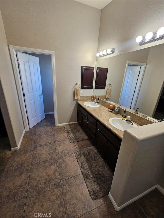 full bathroom featuring double vanity, baseboards, and a sink