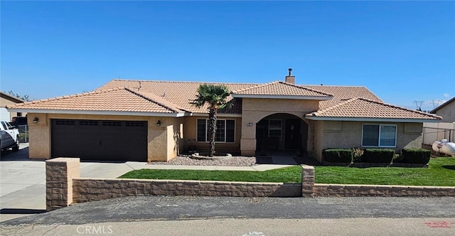 view of front facade featuring a chimney, stucco siding, concrete driveway, an attached garage, and a tiled roof