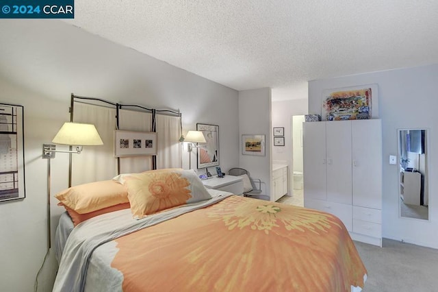 bedroom featuring ensuite bath, light colored carpet, and a textured ceiling