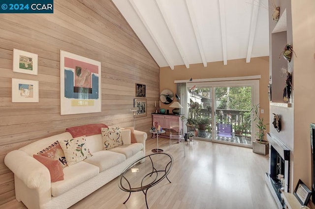 living room with lofted ceiling with beams, light hardwood / wood-style flooring, and wood walls