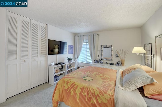 bedroom featuring light colored carpet, a textured ceiling, and a closet