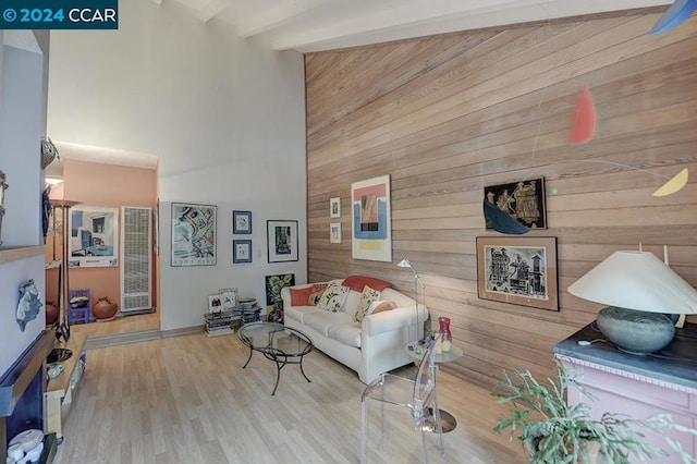 living room with beamed ceiling, light hardwood / wood-style flooring, and wood walls