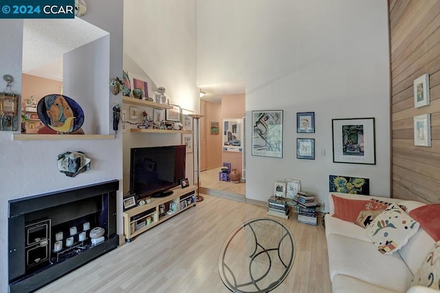 living room featuring wooden walls, wood-type flooring, and vaulted ceiling