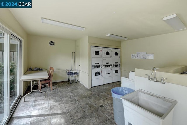 clothes washing area with stacked washer / drying machine and sink