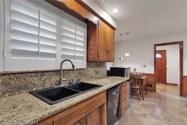 kitchen featuring black dishwasher, tasteful backsplash, hanging light fixtures, light stone countertops, and sink