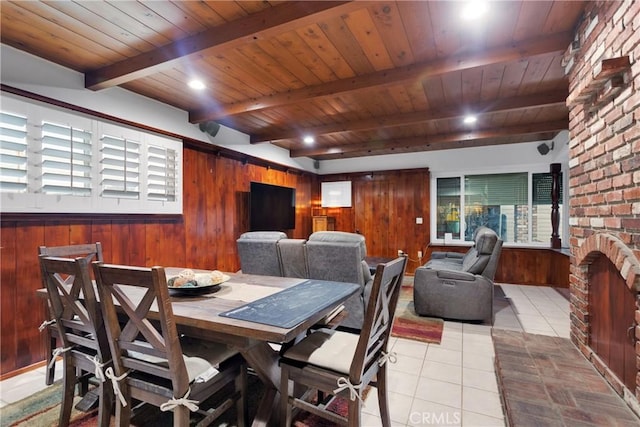 tiled dining area with a fireplace, beamed ceiling, wood walls, and wooden ceiling