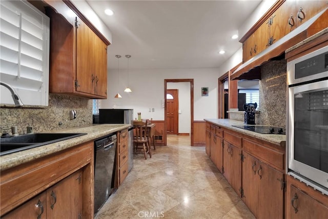 kitchen with hanging light fixtures, decorative backsplash, black appliances, and sink