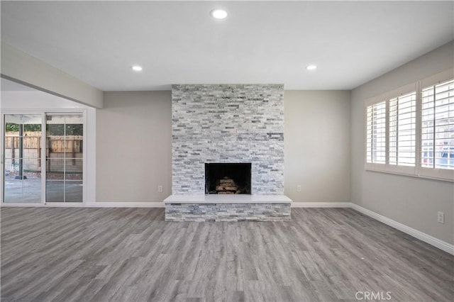 unfurnished living room with a stone fireplace and wood-type flooring